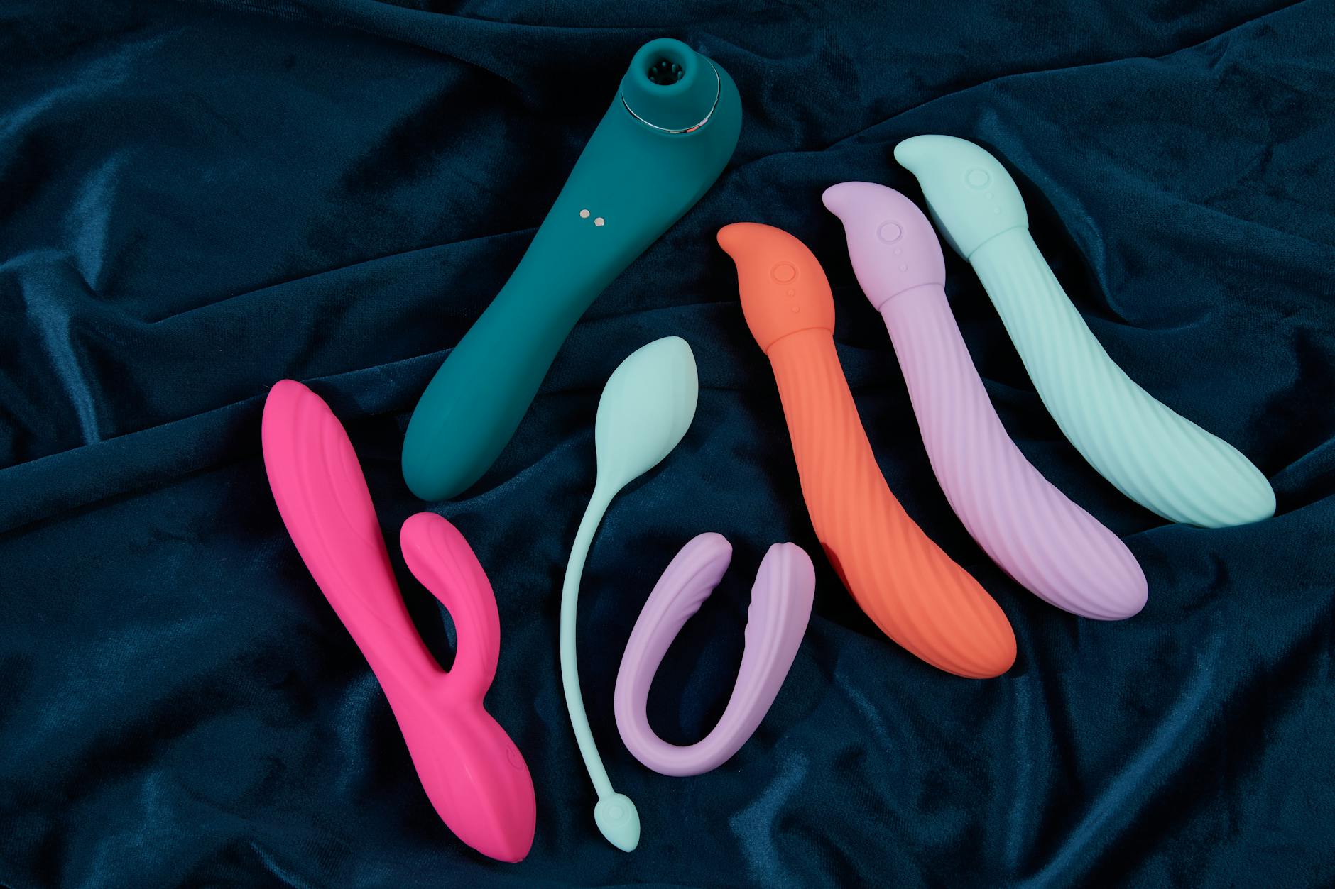 Vibrant collection of silicone lemon vibrators and clitoral toys in various colors displayed on dark fabric