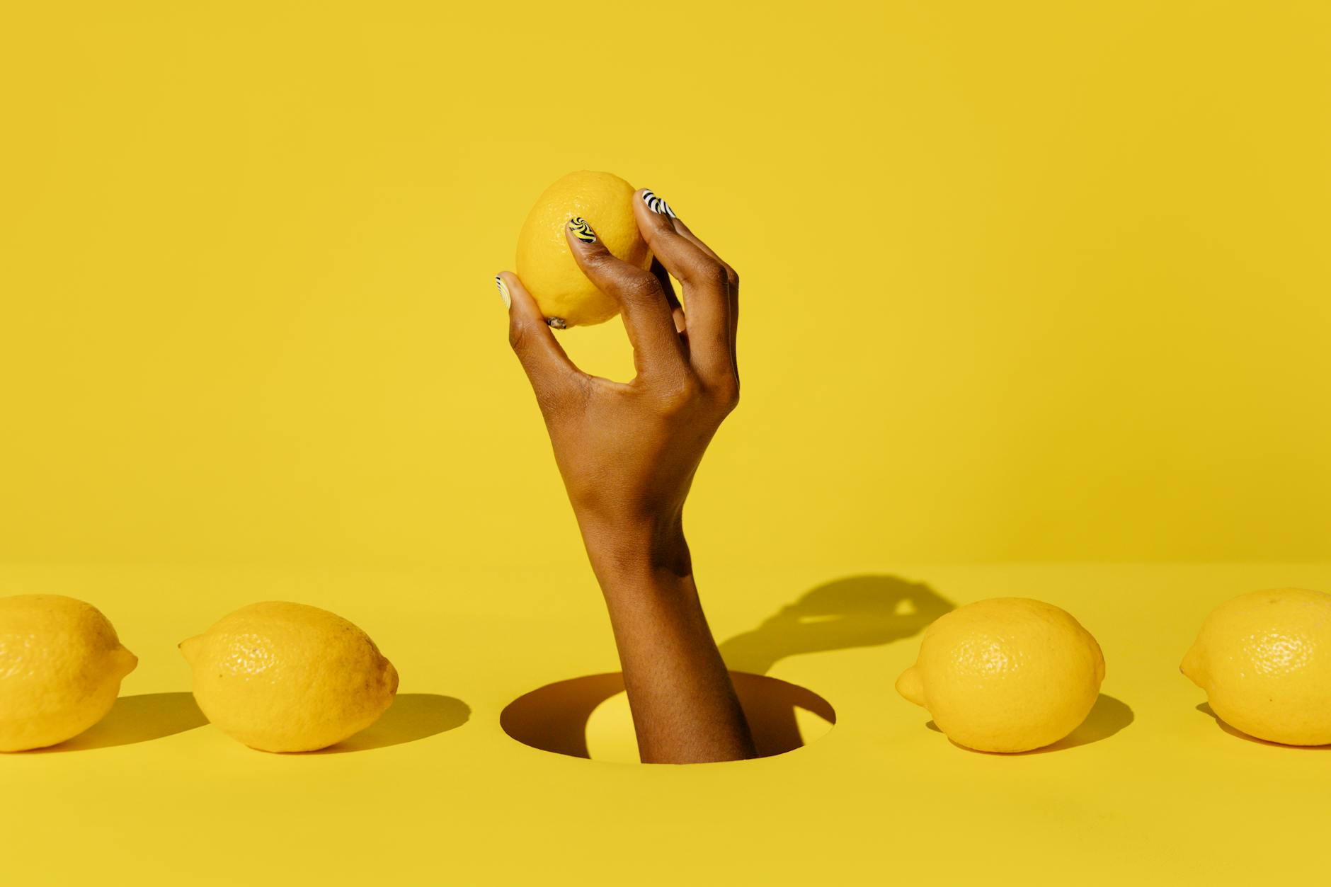 A hand holding a lemon against a vivid yellow background, symbolizing freshness and safe exploration
