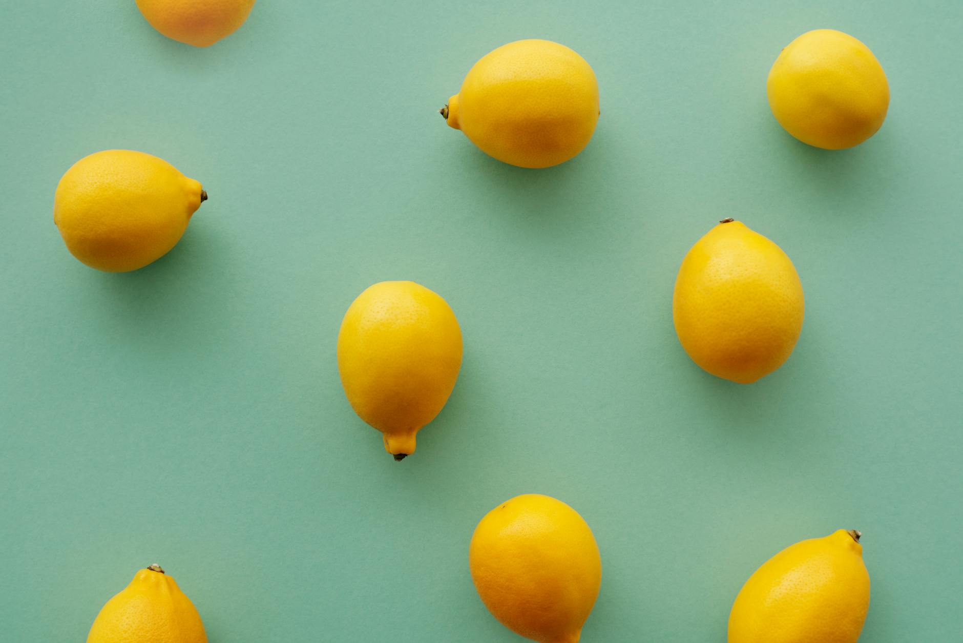 Bright yellow lemons arranged on a pastel green background, symbolizing refreshing reset and renewal of sensation
