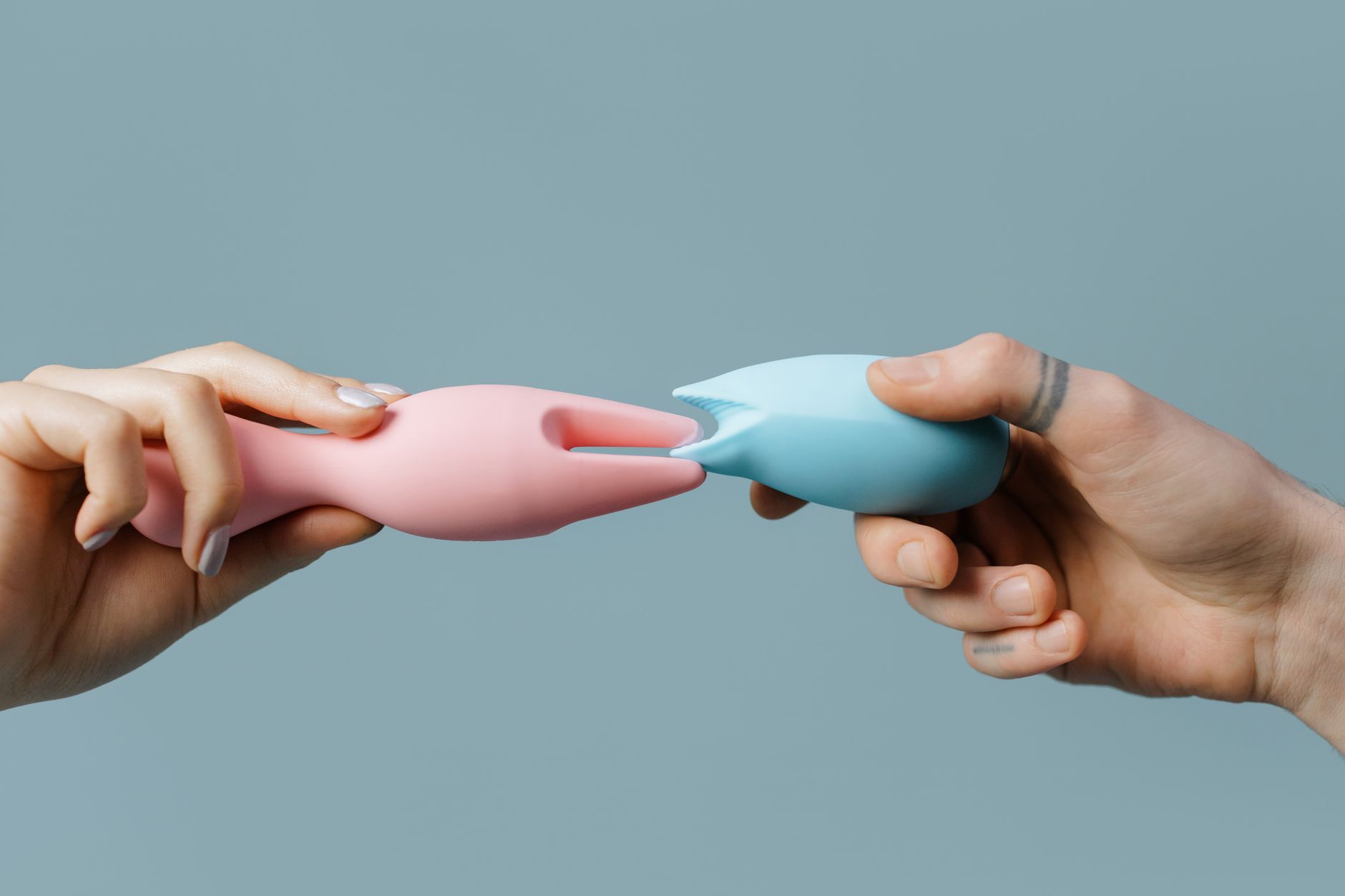 Hand holding a blue silicone sex toy against purple background, representing self-love and personal pleasure