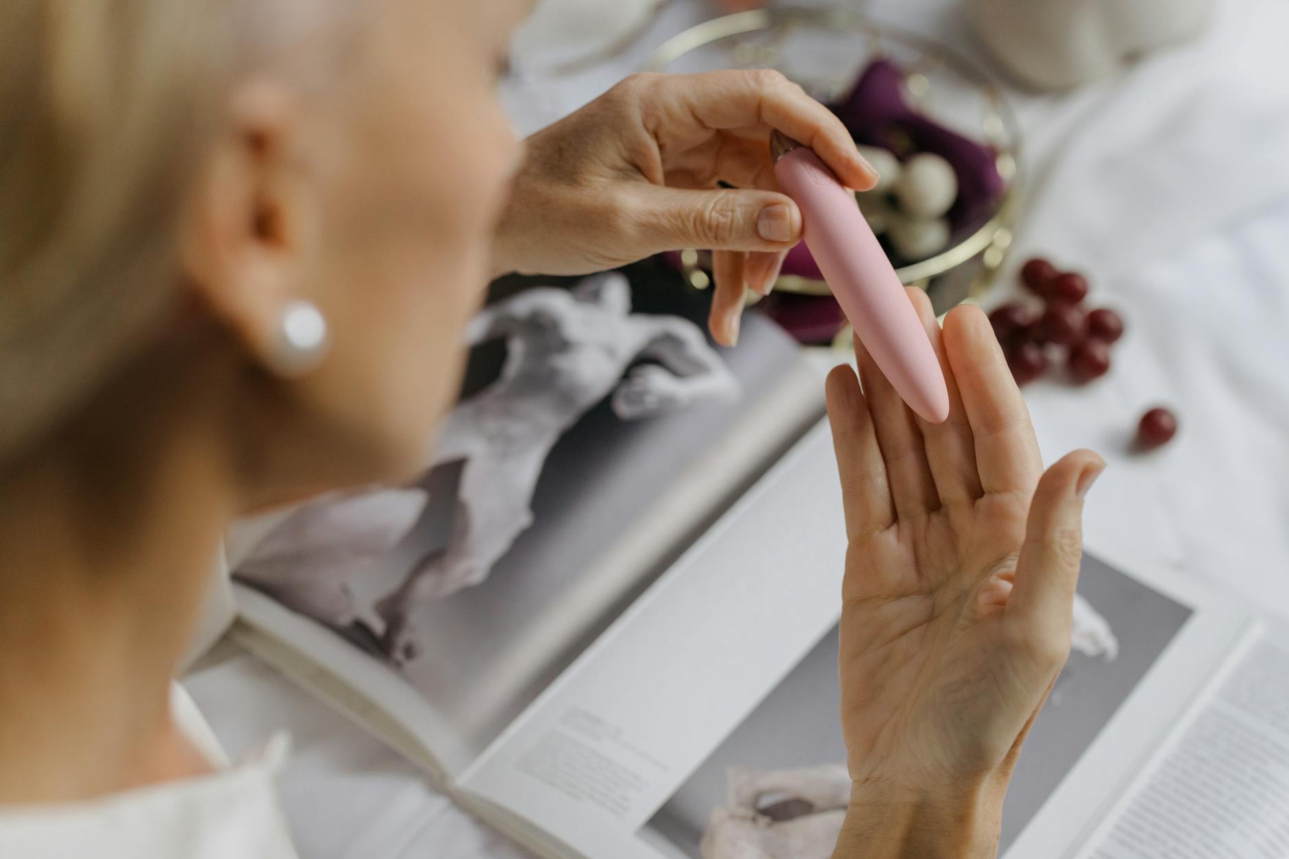 Close-up of a woman holding a pink vibrator, exploring pleasure and intimacy after major life transitions.