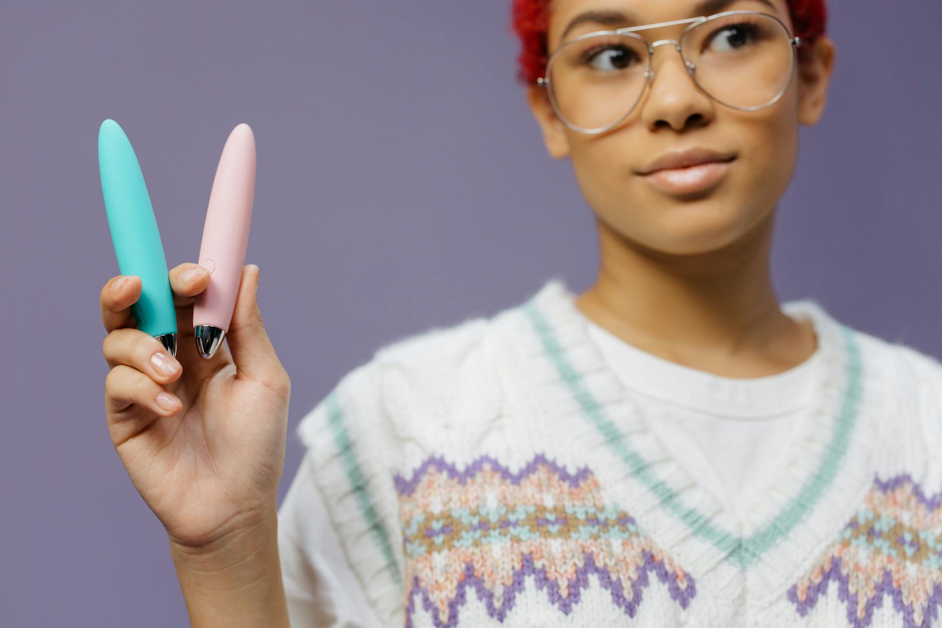Two colorful vibrators held together against a purple background, representing partnership and shared pleasure