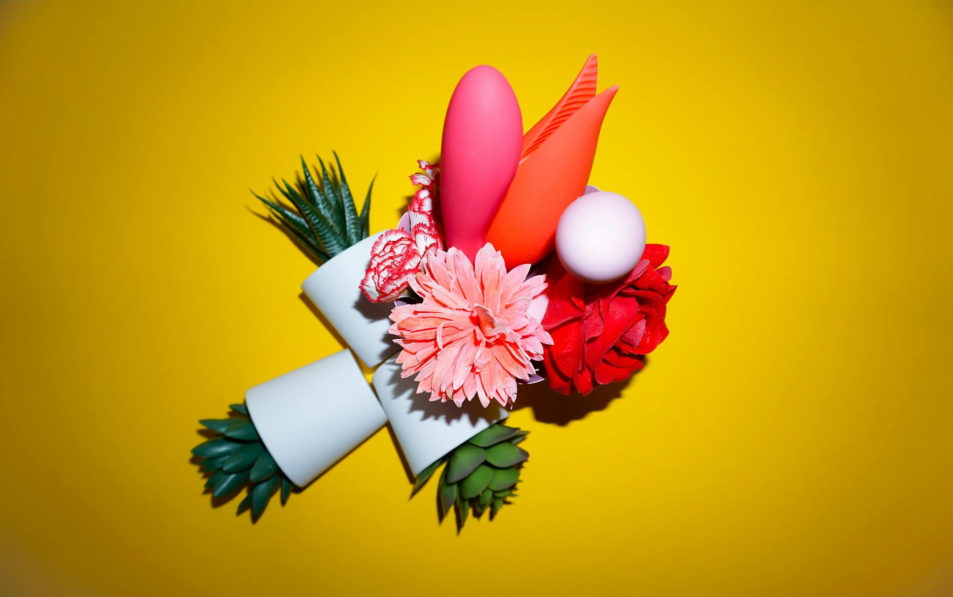Hand reaching over colorful lemon vibrators and adult toys arranged on a table