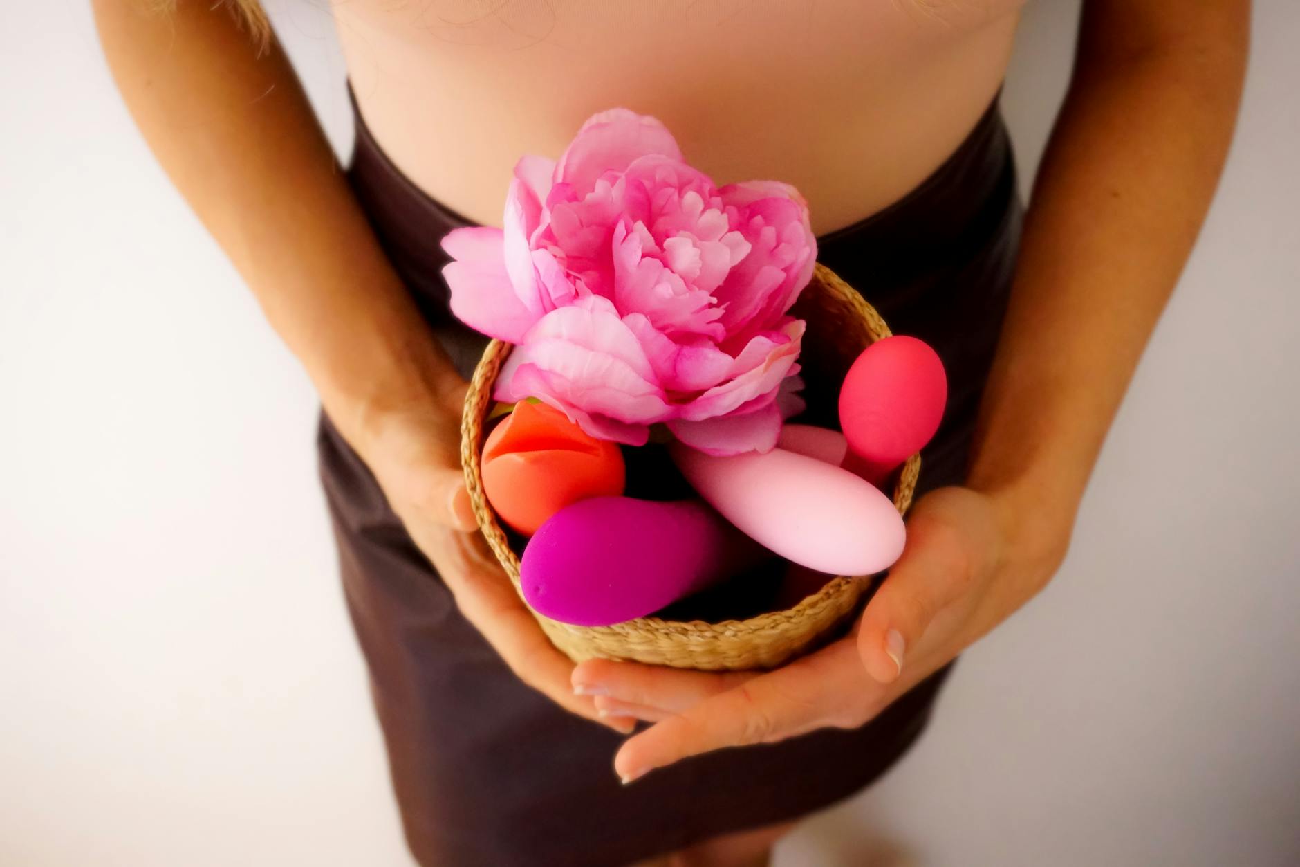 A blue vibrator surrounded by flowers and citrus on a bright yellow background